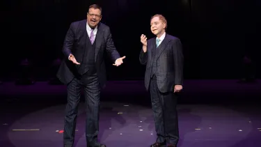 Two men in a suit performing on the stage.